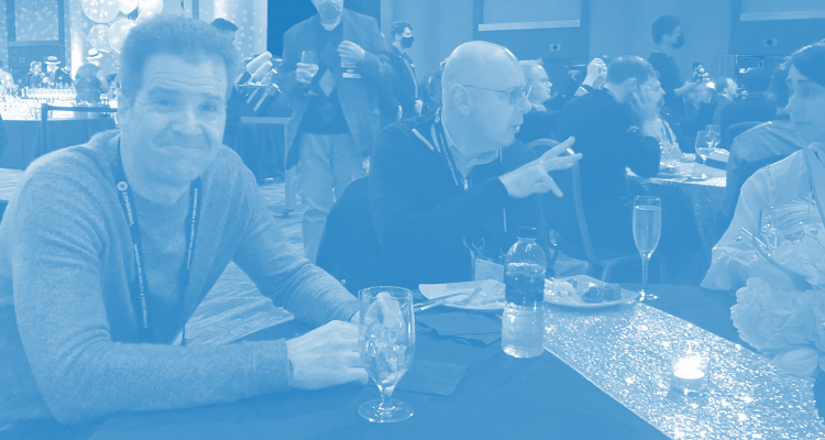 David Spinks and Gerard Zytnicki sit at a table at an SPIE 2022 party