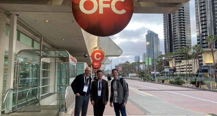 Gerard, Lewis, and David at OFC 2022. They're standing under the OFC conference sign outside of the conference center in San Diego