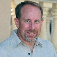 Headshot of Brad Booth, a white man with short pale hair and a goatee. He's wearing a collared short that's a light blue.