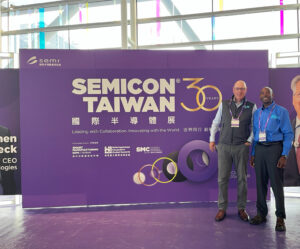 Gerard and Delwin stand in from the the SEMICON Taiwan 30 giant purple conference sign